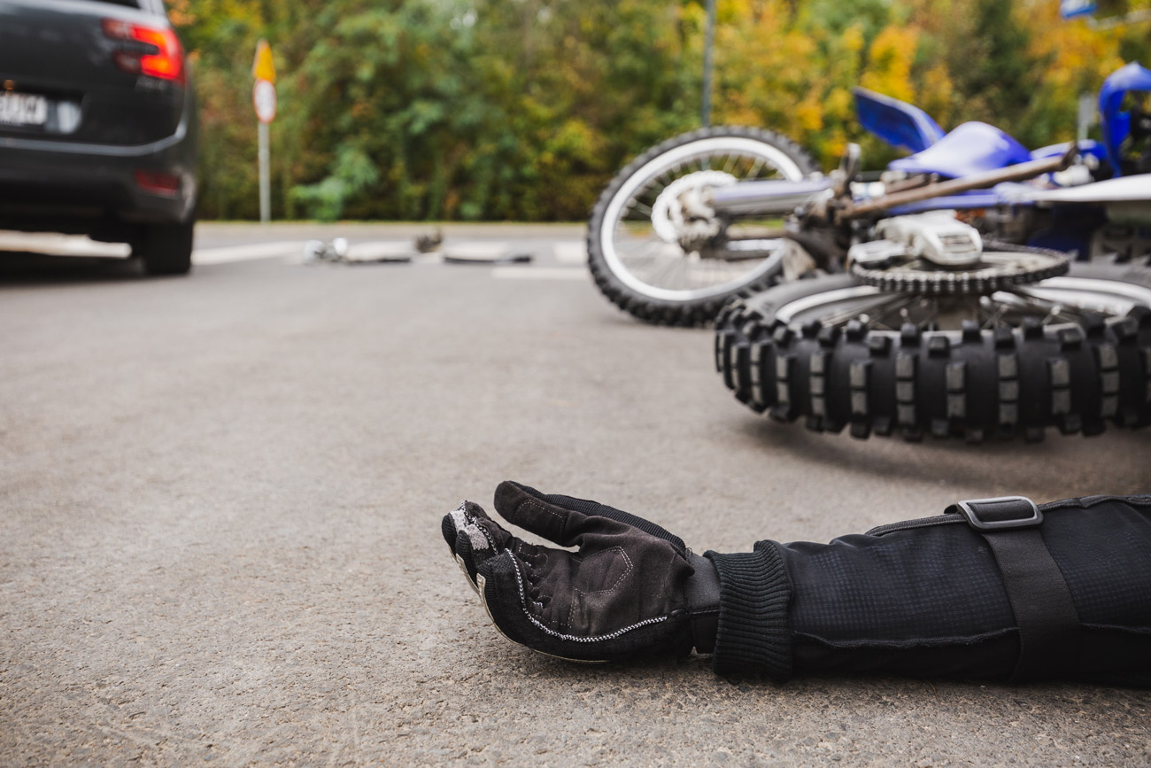 Motorcycle accident victim laying on the ground with their motorcycle in the background