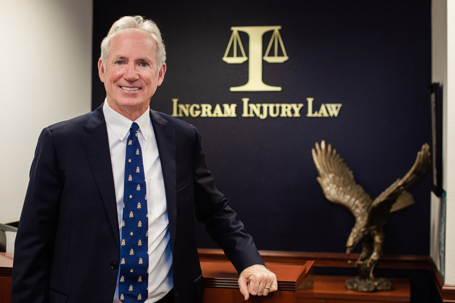 Attorney Timothy M. Ingram, Sr. posing in his office at the front desk with the Ingram Injury Law logo on the wall