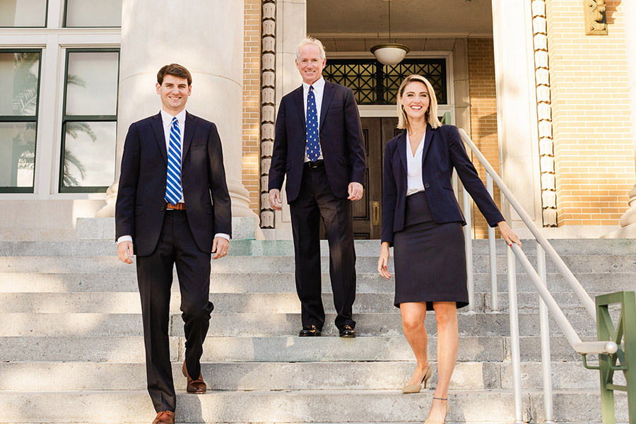 Ingram Injury Law attorneys Timothy M. Ingram, Jr., Timothy M. Ingram, Sr., & Megan E. Ingram posing on the stairs infront of a courthouse in Clearwater, Florida